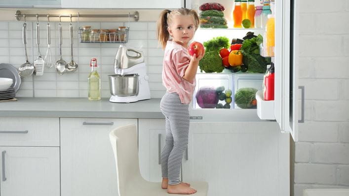 Cuánto se ahorra con electrodomésticos clase A: una niña coge una manzana de un frigorífico