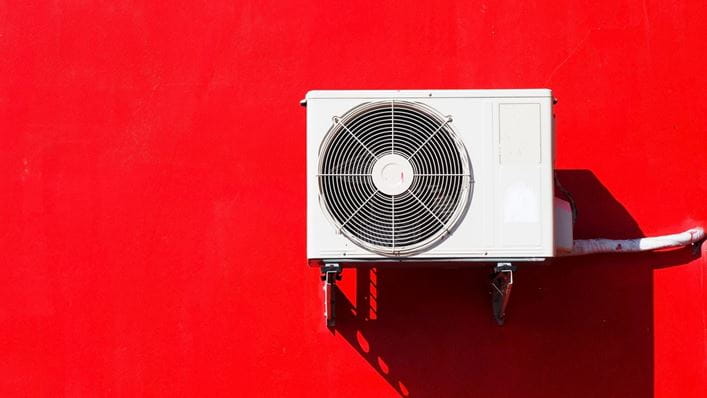 Unidad exterior de aire acondicionado en una fachada roja