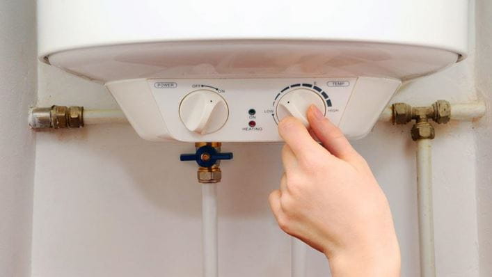 Mano de mujer girando el termostato de un calentador eléctrico
