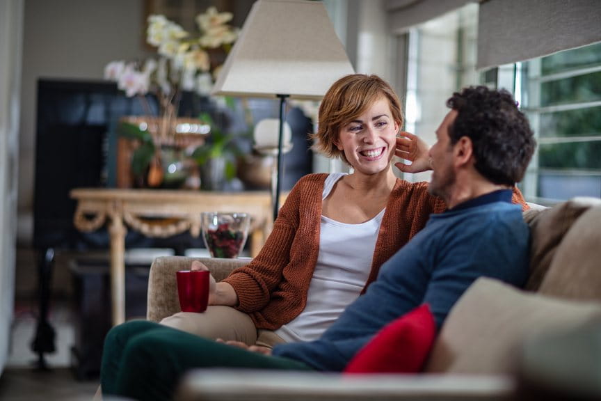 Pareja sentada en el sofá del salón con una lámpara al fondo