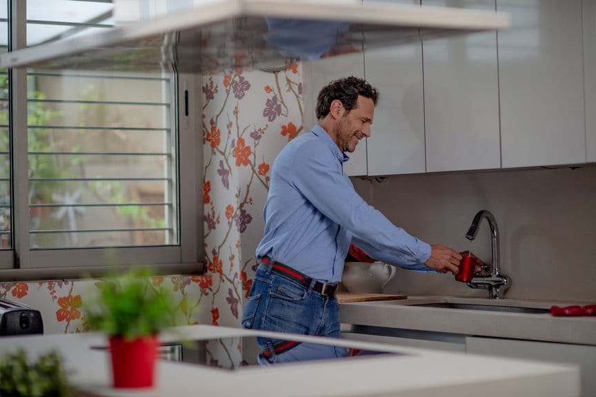 Hombre utilizando el grifo de su cocina