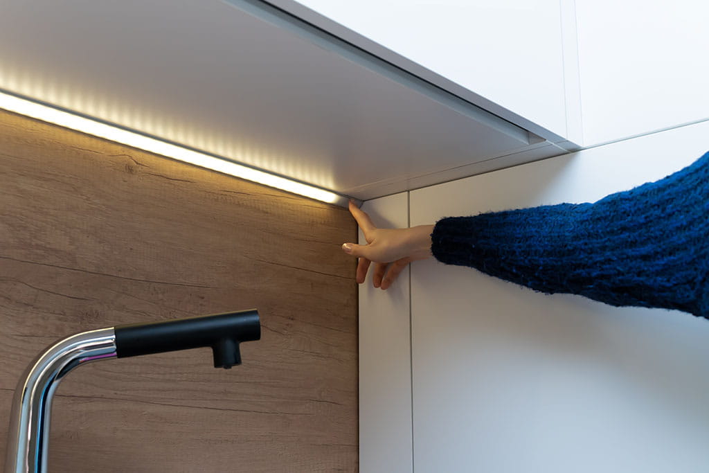 Una mujer coloca tiras de led en la cocina