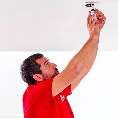 Un electricista de HomeServe cambiando las bombillas de la casa de un cliente