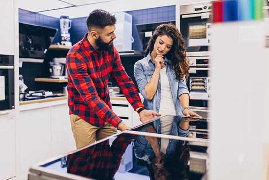 Pareja joven feliz comprando una placa de inducción