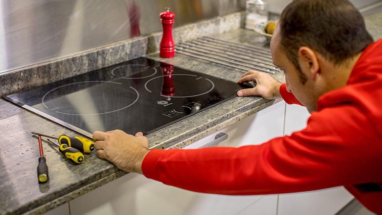 Técnico de reparación de vitrocerámicas de HomeServe en la cocina de unos clientes