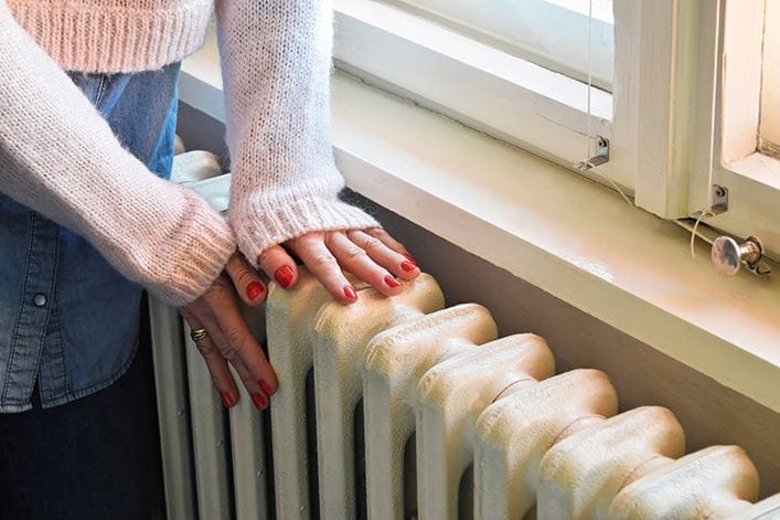 manos de mujer tocando un radiador de calefacción eficiente