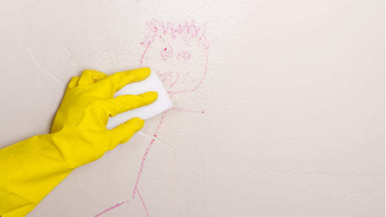 Mano con guante limpiando un dibujo de la pared con borrador mágico