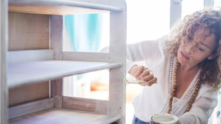 Mujer pintando un mueble de blanco