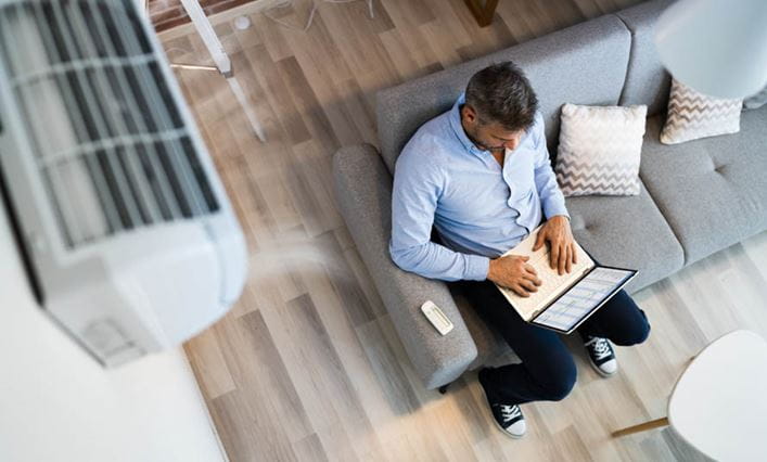 Un hombre consultando su ordenador en su apartamento con aire acondicionado A+++.