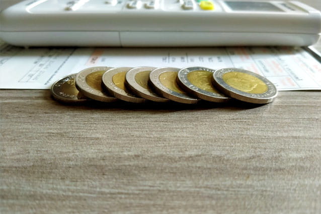 Monedas delante de un mando de aire acondicionado como símbolo de ahorro