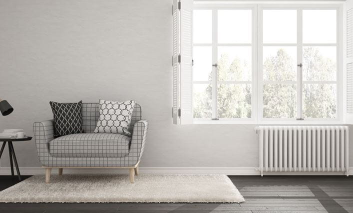 Radiador blanco debajo de una ventana de una habitación