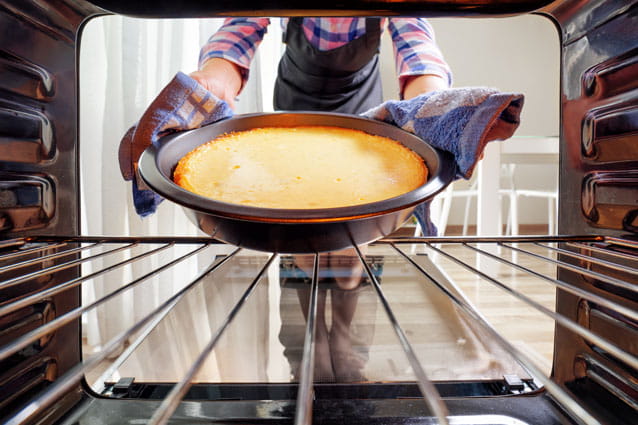 Una mujer sacando una tarta de manzana del interior de un horno eléctrico