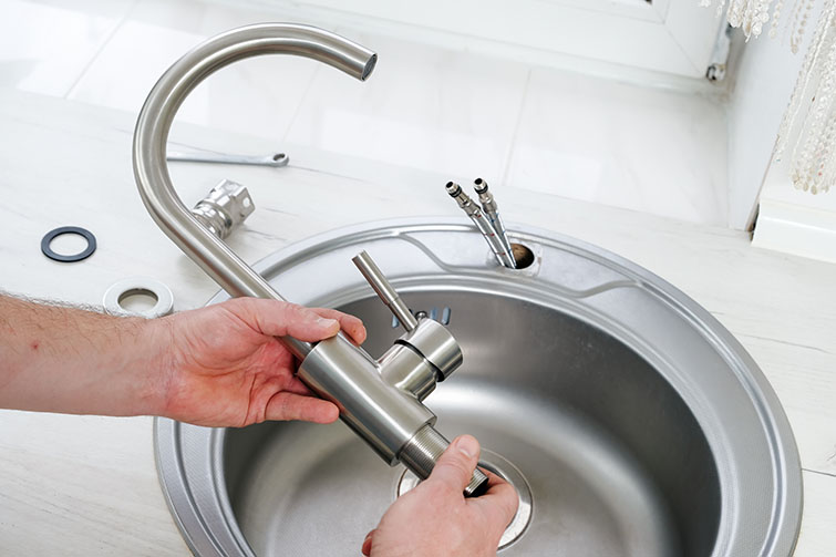 Un hombre reparando un grifo de la cocina