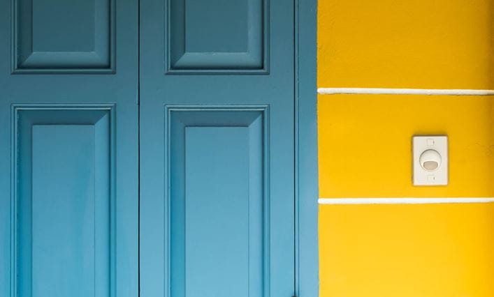 Puerta azul de madera con un timbre zumbador al lado