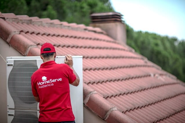 Técnico en aire acondicionado de HomeServe limpiando la unidad exterior