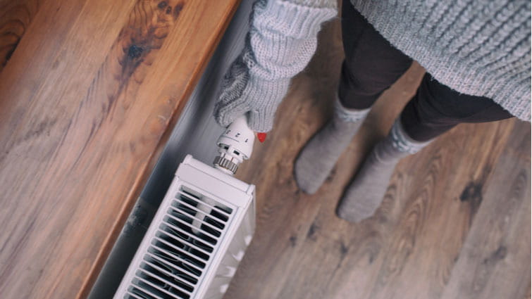 Mujer manipula un radiador de calefacción durante las horas recomendadas