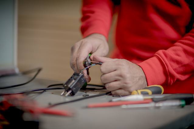 Electricista de HomeServe empalmando los cables de unas luces de Navidad