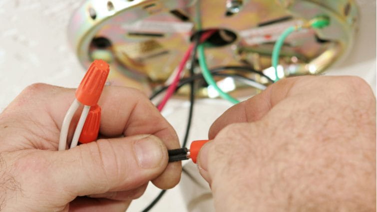 Manos de hombre empalmando los cables de un ventilador de techo