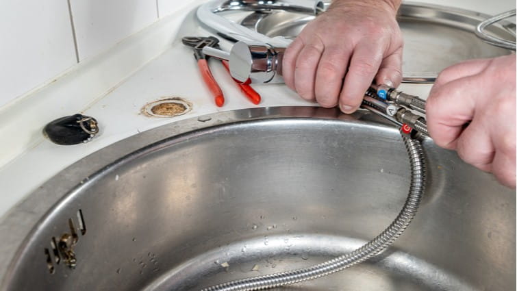 Manos de hombre cambiando un grifo de cocina