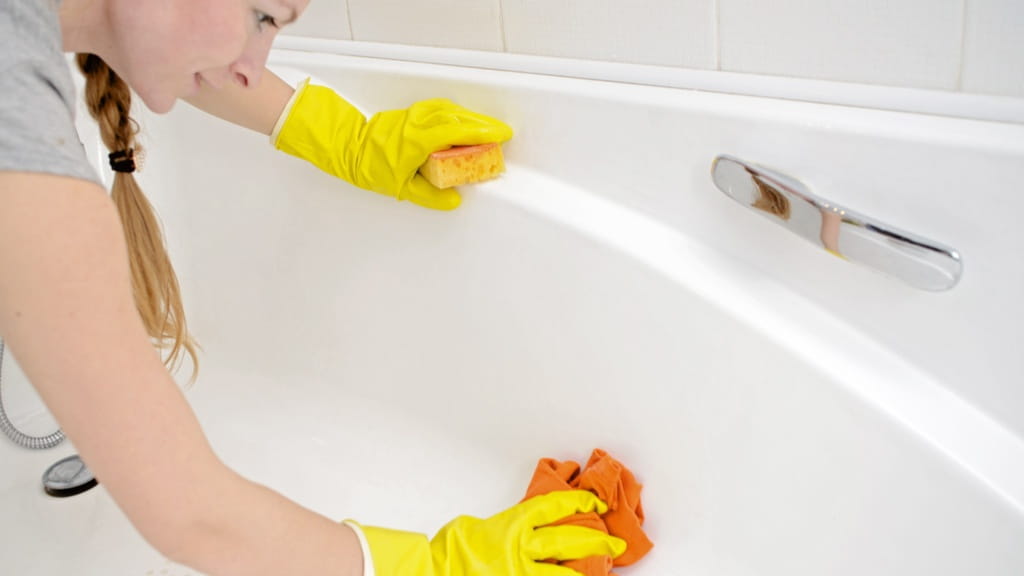 Mujer con guantes limpiando la bañera