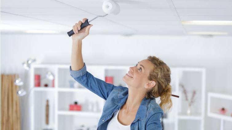 Mujer pintando el techo con un rodillo