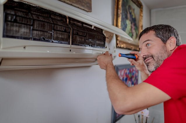 Un técnico de aire acondicionado de HomeServe revisando un aire acondicionado