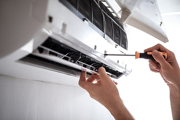 Tecnico de aire acondicionado de HomeServe reparando un aire acondicionado que no enfria