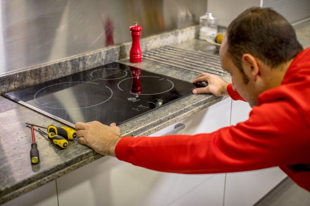 Un técnico de reparación de vitrocerámicas de HomeServe arreglando una vitrocerámica que esta bloqueada