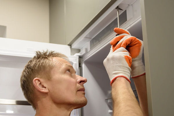 Técnico de electrodomésticos de HomeServe reparando una nevera que no congela
