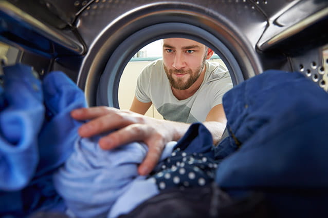 Un hombre carga la lavadora con demasiada ropa