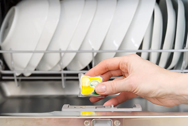 Una mujer coloca una pastilla de detergente en el lavavajillas