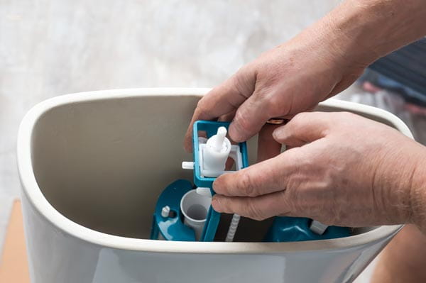 Mano dentro de una cisterna que no deja de echar agua