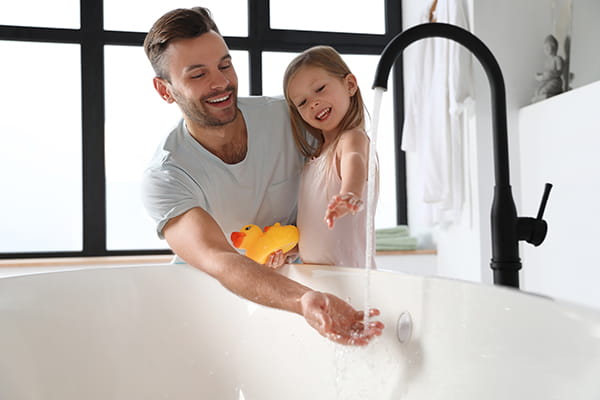 Padre con su hija abriendo un grifo termostatico que gotea