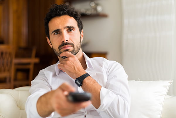 Hombre con un mando intentando sintonizar canales tv