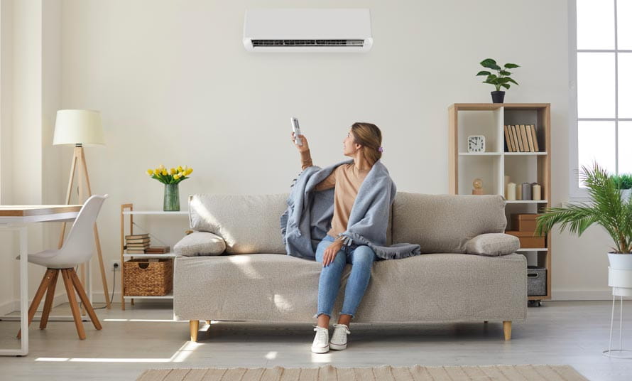 Mujer en un sofá regulando la temperatura del aire en invierno