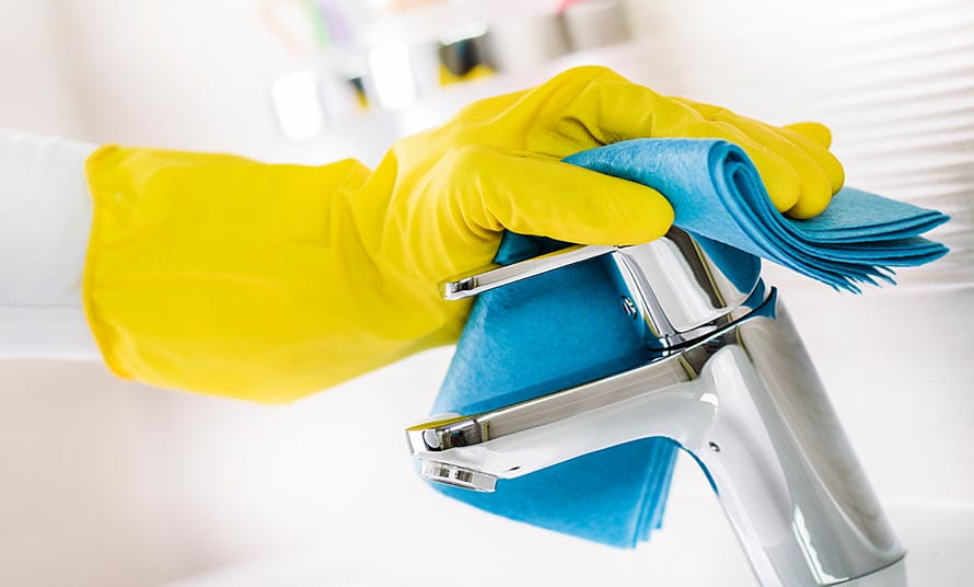 Una persona limpiando el grifo de un cuarto de baño
